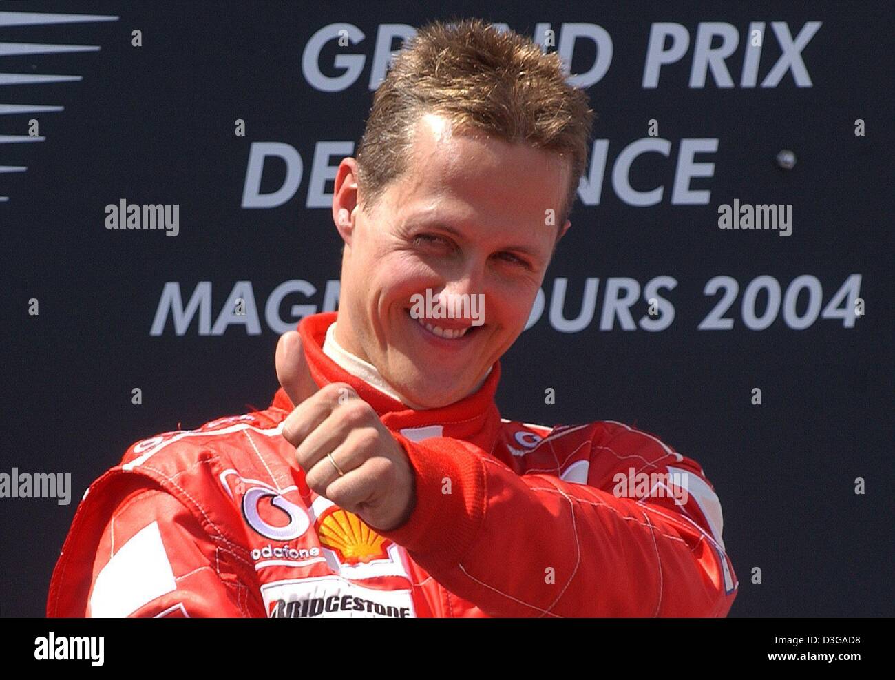 (Dpa) - Pollice su: tedesco pilota di Formula Uno Michael Schumacher (Ferrari) cheers dopo aver vinto il Gran Premio di Francia in Magny Cours racing corso in Francia, il 4 luglio 2004. Il sei volte campione del mondo Schumacher ha vinto la sua nona gara della stagione, matching il suo record di sette vittorie in una sola gara. Ora egli è anche proprietaria della prima vittoria in F1 con quattro deliberata di pit-stop. Foto Stock