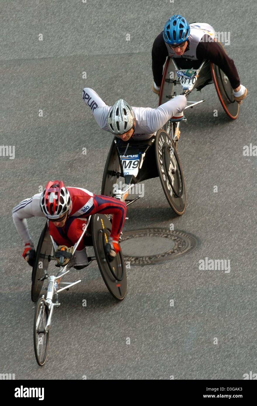 (Dpa) - tre atleti in carrozzina ritmo lungo una strada come parte di circa 20.000 corridori provenienti da 72 paesi che partecipano alla XIX maratona di Amburgo, che copre una distanza di 42.195 chilometri attraverso il greate città portuale di Amburgo, Germania, 18 aprile 2004. Foto Stock