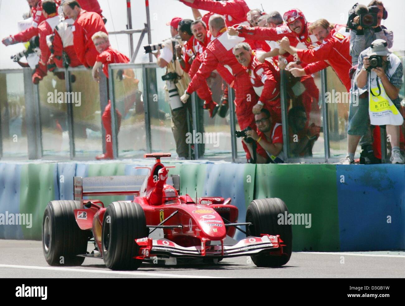 (Dpa) - Il team Ferrari jubilate come vincitore del Gran Prix Michael Schumacher rigidi da dopo il Gran Premio di Francia in Magny Cours racing corso in Francia, il 4 luglio 2004. Il sei volte campione del mondo Schumacher ha vinto la sua nona gara della stagione, matching il suo record di sette vittorie in una sola gara. Ora egli è anche proprietaria della prima vittoria in F1 con quattro deliberata di pit-stop. Foto Stock