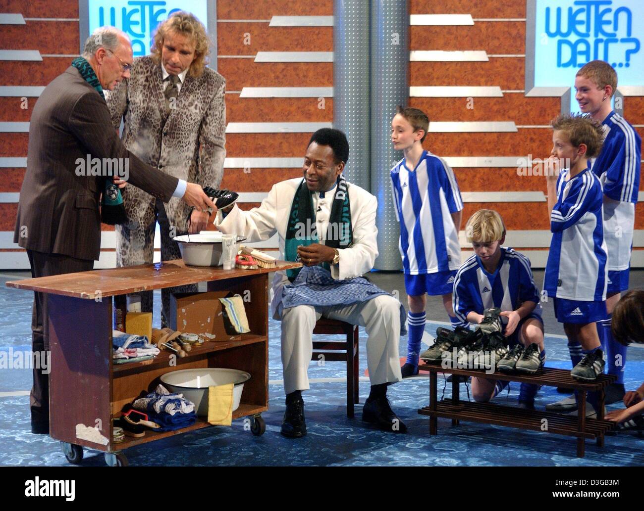 (Dpa) - Ex brasiliano della star del calcio Edson Arantes do Nascimento, aka. Pele (abito bianco), ha per pulire le scarpe dopo aver perso la sua scommessa durante il tedesco show televisivo "Wetten Dass...?" (bet che...?) a Leipzig, Germania, 13 novembre 2004. Calcio tedesco leggenda Franz Beckenbauer (L) e host TV Thomas Gottschalk (2a da L) stanno aiutando. La mascotte per il 2006 Coppa del Mondo in Ge Foto Stock