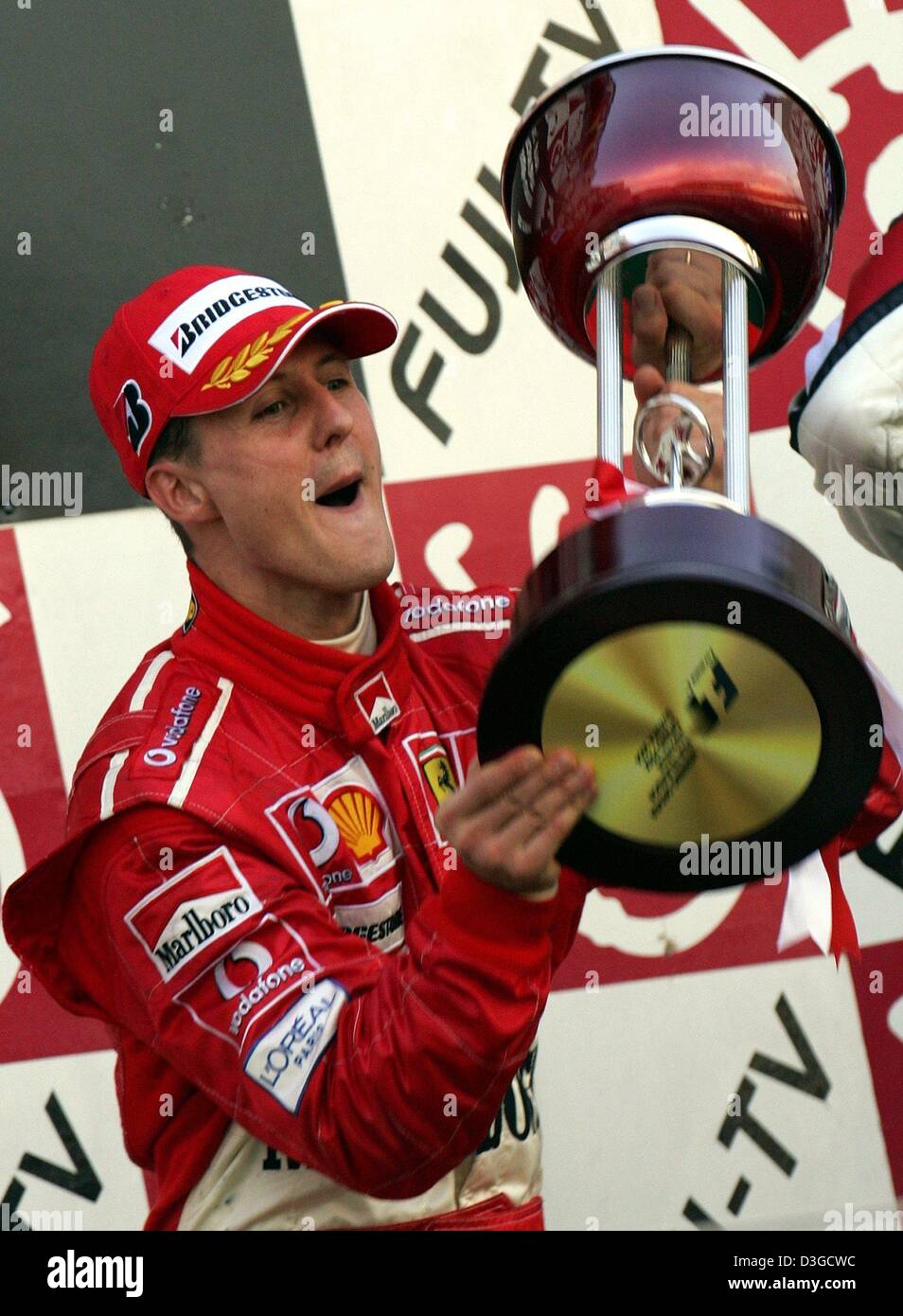 (Dpa) - Michael Schumacher (Ferrari), tedesco pilota di Formula Uno, cheers durante la cerimonia di consegna del premio dopo aver vinto il Gran Premio di Formula Uno racing circuito di Suzuka, in Giappone, 10 ottobre 2004. Michael Schumacher ha vinto la gara seguito da suo fratello che è arrivato secondo. Foto Stock