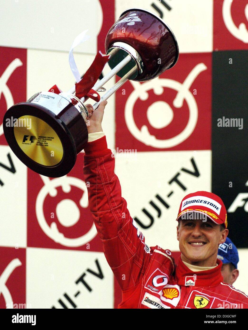 (Dpa) - Michael Schumacher (Ferrari), tedesco pilota di Formula Uno, cheers durante la cerimonia di consegna del premio dopo aver vinto il Gran Premio di Formula Uno racing circuito di Suzuka, in Giappone, 10 ottobre 2004. Michael Schumacher ha vinto la gara seguito da suo fratello che è arrivato secondo. Foto Stock