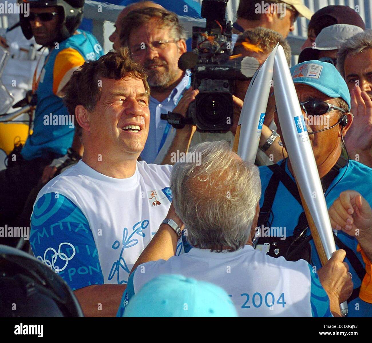 (Dpa) - Otto Rehhagel (L), il tedesco-nato allenatore della nazionale greco di squadra di calcio che ha vinto l'Euro 2004 campionati di calcio, assume la fiamma olimpica in Atene, 8 agosto 2004. Rehhagel porterà la fiamma sul Rio Antirio bridge in Grecia occidentale. La torcia olimpica giungerà ad Atene durante i Giochi aprire il 13 agosto. Foto Stock