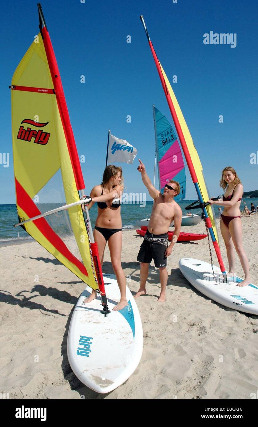 (Dpa) - Surf istruttore Philipp Schwarz (C) spiega le nozioni di base di sport a ansiosi gli studenti durante il corso introduttivo sulla isola di Ruegen, Germania, 18 luglio 2004. Ogni anno da giugno a settembre la scuola di surf insegna alle persone circa le tavole da surf e vela sul Mar Baltico spiagge. Foto Stock