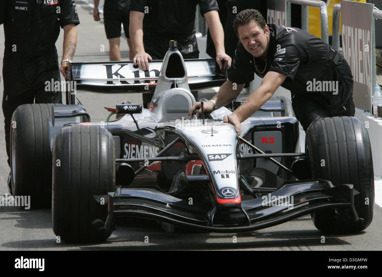 (Dpa) - i meccanici della McLaren Mercedes spingono la nuova formula one racing car verso il garage per ulteriori scruteneering al circuuit corse a Magny Cours in Francia, 1 luglio 2004. Il nuovo modello sostituisce il vecchio e non riuscito MP18 modello. Il Gran Premio di Francia inizia il 04 luglio 2004. Foto Stock