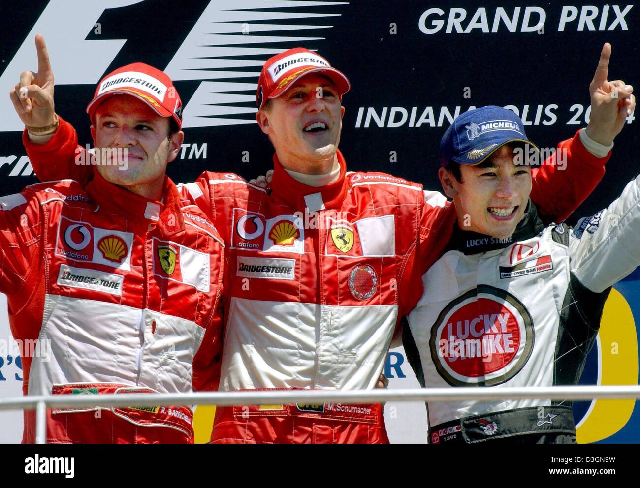 (Dpa) - Tedesco pilota di Formula Uno Michael Schumacher (C) della Ferrari cheers e celebra insieme con la sua collega di squadra del pilota brasiliano Rubens Barrichello (L), che ha preso il secondo posto, e il pilota giapponese Takuma Sato di BAR Honda, che ha colto il terzo posto, dopo aver vinto il Gran Premio degli Stati Uniti a Indianapolis, Stati Uniti d'America, 20 giugno 2004. Foto Stock