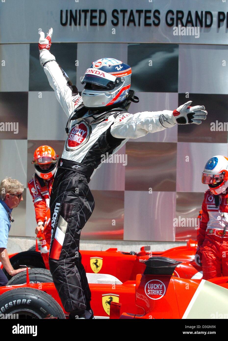 (Dpa) - Giapponese pilota di Formula Uno di Takuma Sato di BAR Honda cheers e danze accanto a una Ferrari Formula One racing car dopo aver tenuto il terzo posto in noi Gran Premio di Indianapolis, Stati Uniti d'America, 20 giugno 2004. Foto Stock