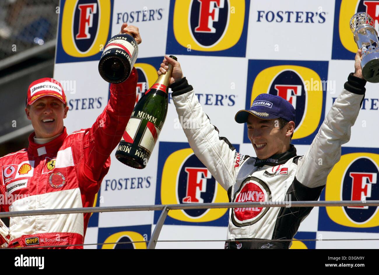 (Dpa) - Tedesco pilota di Formula Uno Michael Schumacher (C) della Ferrari cheers e celebra insieme al pilota giapponese Takuma Sato di BAR Honda dopo aver vinto il Gran Premio degli Stati Uniti a Indianapolis, Stati Uniti d'America, 20 giugno 2004. Sato ha colto un terzo posto. Foto Stock