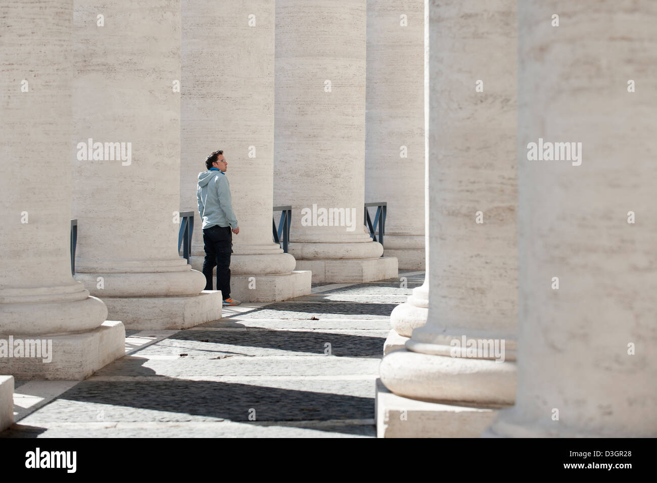 L'uomo cammina nel colonnato di Piazza San Pietro. Foto Stock