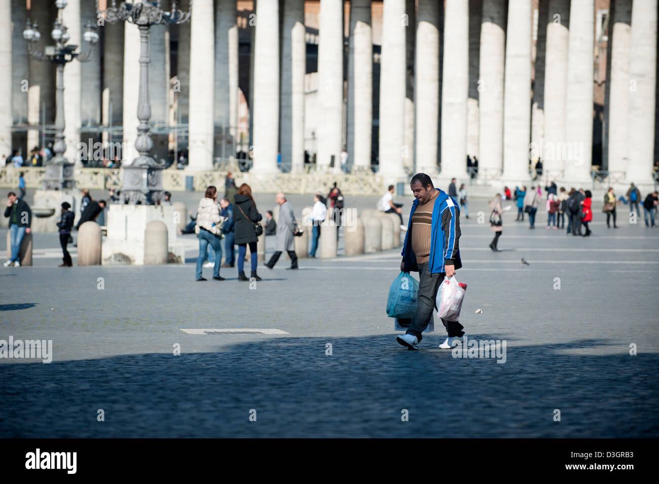 Uomo a piedi in Piazza San Pietro con i sacchetti Foto Stock