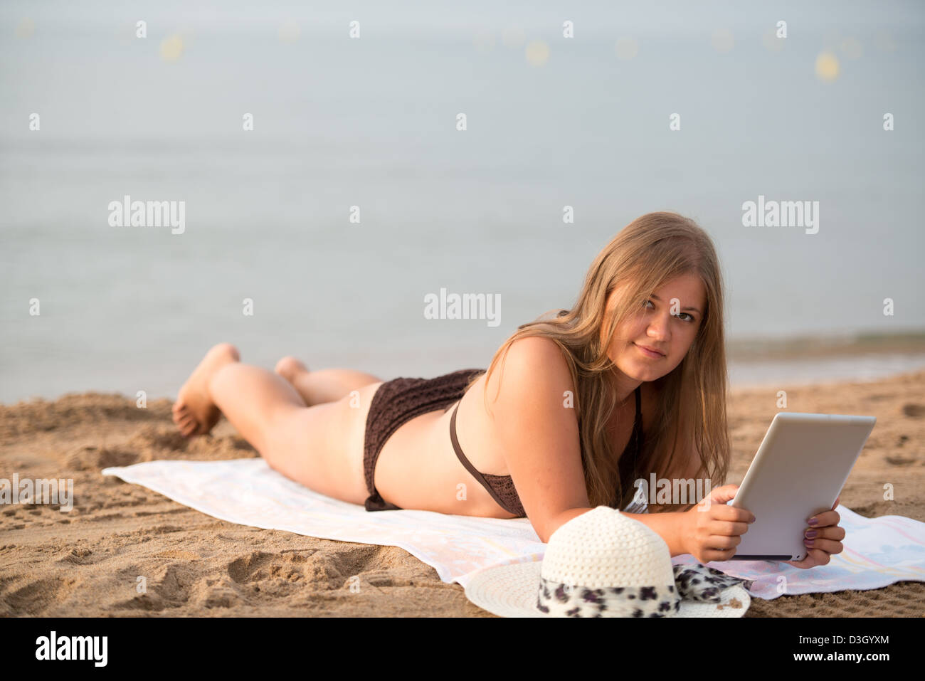 Studentessa sdraiato sulla spiaggia e lavora con i tablet pc Foto Stock