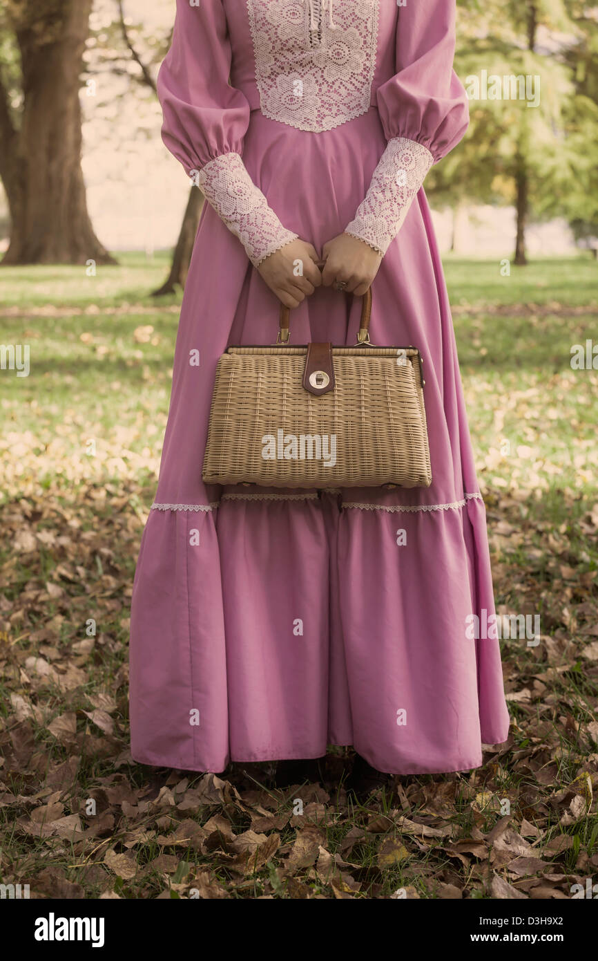 Una donna con un vintage borsetta nel bosco in autunno Foto Stock