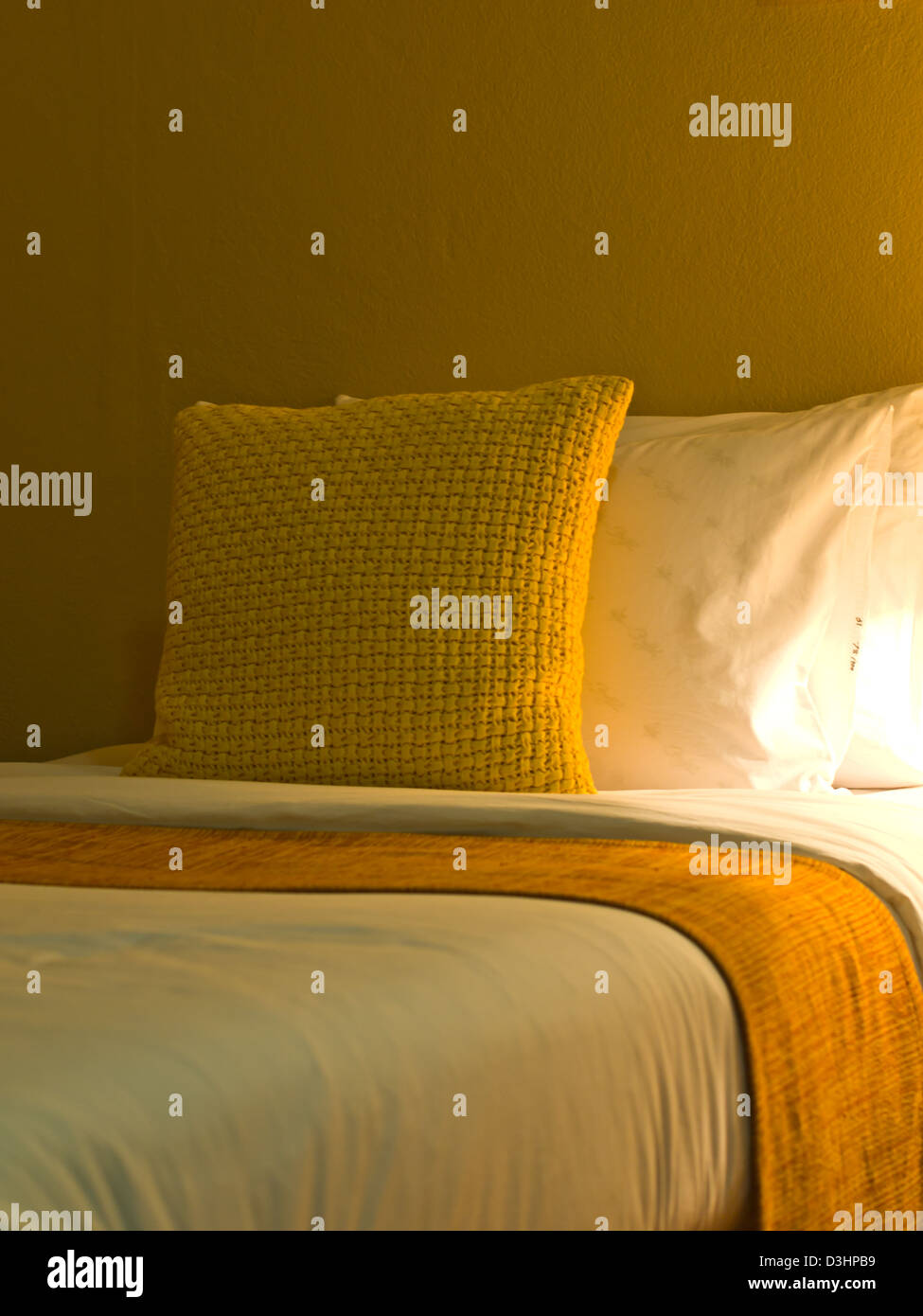 Un design cuscino giallo in un moderno stile interiore camera da letto con una luce calda Foto Stock