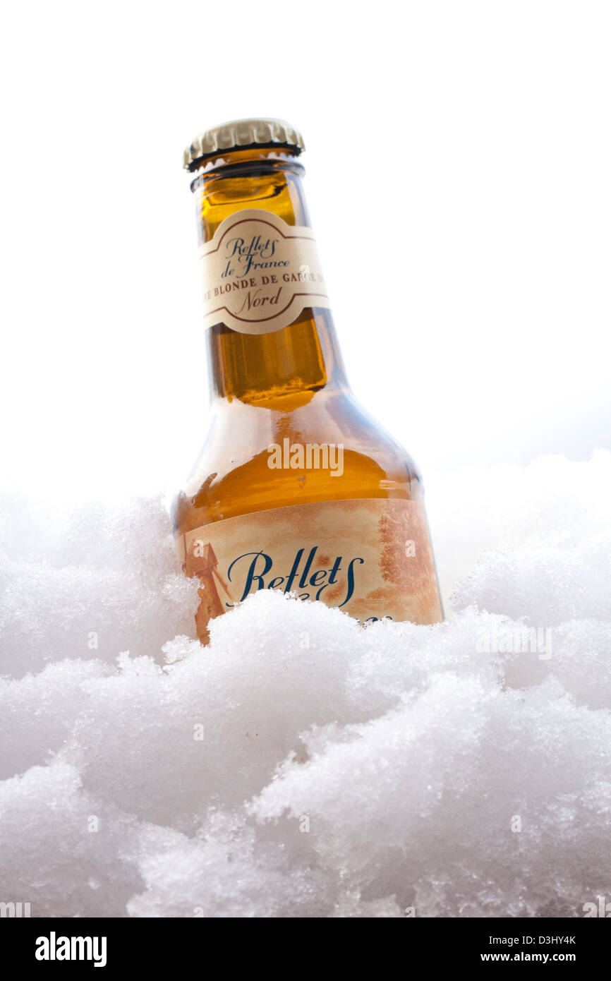 Bionda non aperti bottiglia di birra nella neve Foto Stock