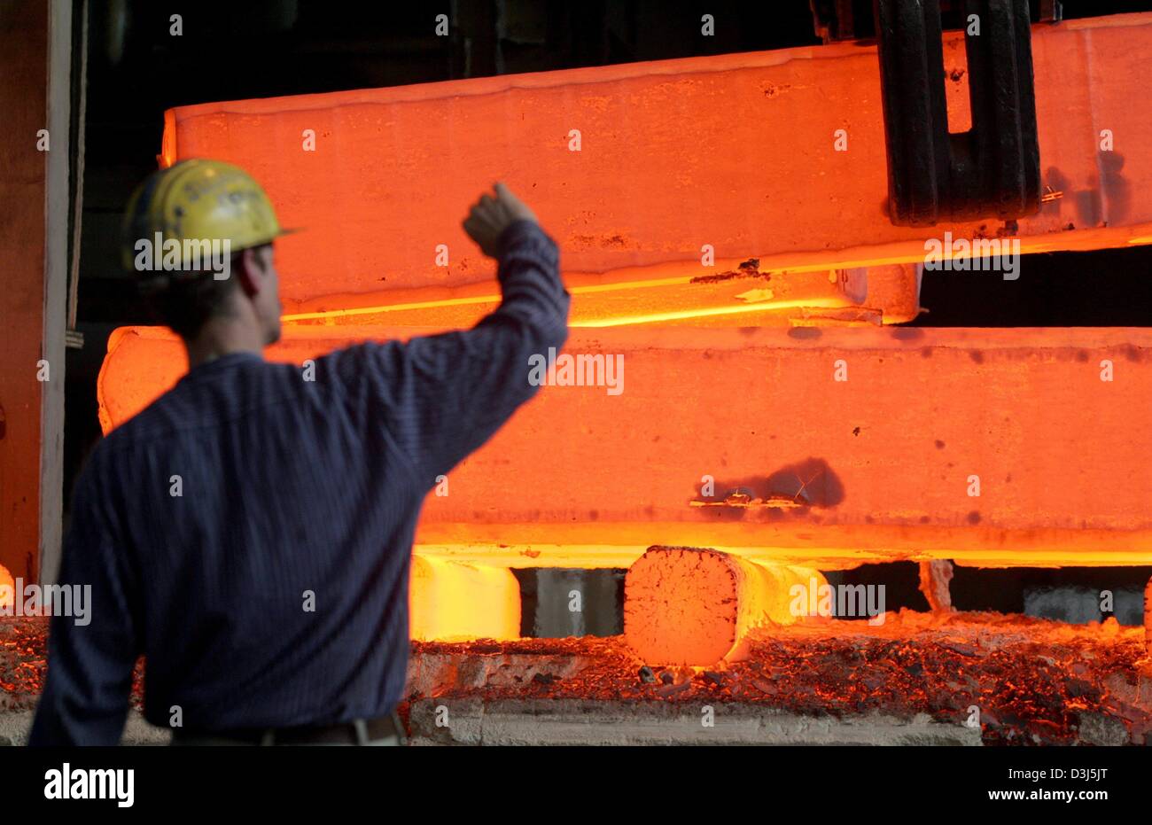 (Dpa) - Un lavoratore tiene per mano di proteggere se stesso dal calore di un blocco incandescente acciaio all'Edelstahlschmiede Witten-Krefeld, acciaio Smith, a Krefeld, Germania, 27 aprile 2004. La società è stata originariamente fondata da Carl Berger nel 1853 e fuse nel 1975 con la Thyssen AG, fondata da industriale tedesco August Thyssen nel 1900. L'azienda divenne nuovamente indipendente nel 1994. Foto Stock