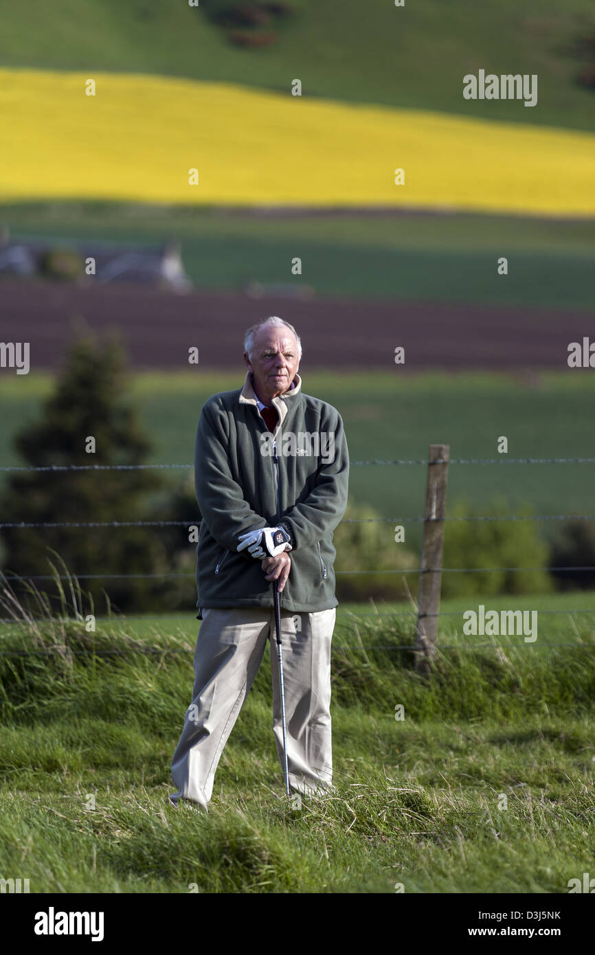 Uomo anziano appoggiato su di un club di golf contemplando come arrivare fuori la ruvida campagna scozzese Foto Stock