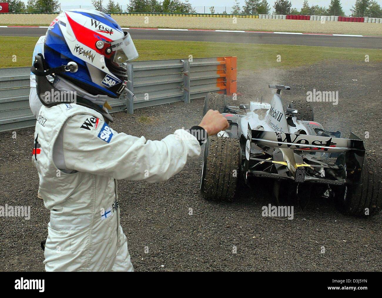 (Dpa) - Finlandese pilota di Formula 1 Kimi Raeikkoenen (McLaren-Mercedes) si allontana dalla cottura a vapore la sua vettura da gara dopo un guasto del motore durante la European F1 Grand Prix al Nurburgring race track, Germania, 30 maggio 2004. Foto Stock