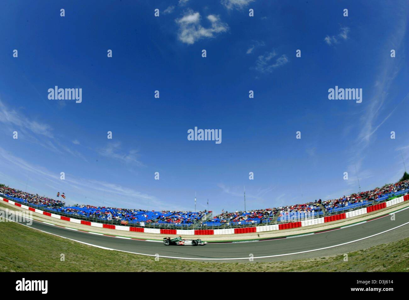 (Dpa) - Una gara di Formula 1 di macchina aziona attraverso una curva sotto un cielo blu al Nuerburgring race course in Germania, 29 maggio 2004. Foto Stock