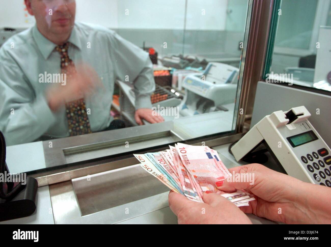 (Dpa) - Un cliente di fronte a una banca teller finestra depositi in denaro nel suo conto presso una filiale di Amburgo Savings Bank ad Amburgo, Germania, 14 aprile 2004. Foto Stock