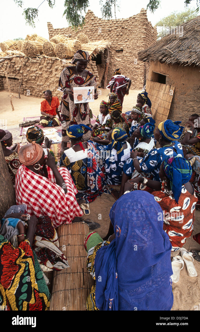 Operatrice di salute rurale femminile che insegna agli abitanti del villaggio migliori pratiche igieniche con tavole da disegno. Burkina Faso Foto Stock