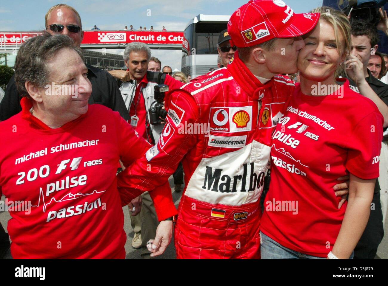 (Dpa) - tedesco di Formula Uno del campione del mondo in carica Michael Schumacher della Ferrari (C) baci moglie Corinna dopo la sua quinta vittoria diritta al Gran Premio di Spagna sul Circuito de Catalunya race track nei pressi di Barcellona, Spagna, 9 maggio 2004. Sulla sinistra la Ferrari del team capitano Jean Todt. Foto Stock