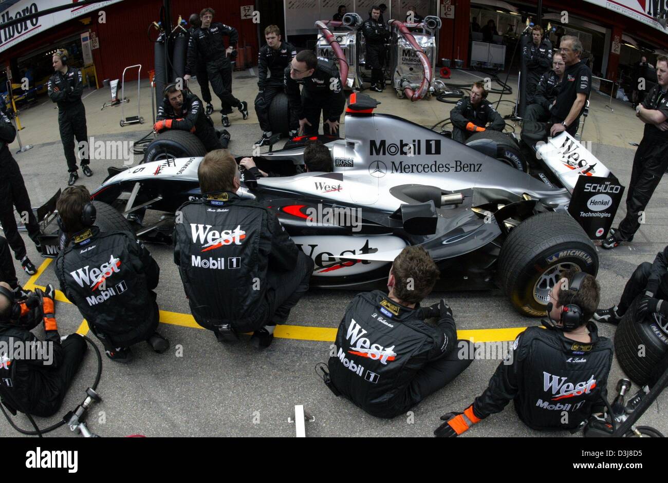 (Dpa) - i meccanici del team McLaren Mercedes sedersi intorno a una formula one racing car durante un pit stop di formazione sul circuito di formula uno di Barcellona, in Spagna, il 6 maggio 2004. Il gran premio di Spagna si terrà questo fine settimana del 8 maggio e del 9 maggio 2004. Foto Stock
