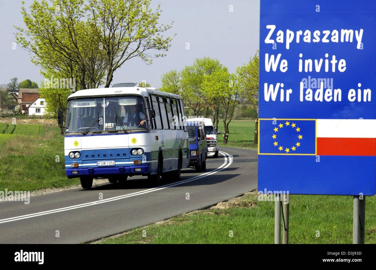 (Dpa) - una unità bus lungo una strada di campagna che passa un cartello stradale che visualizza le bandiere nazionali della Polonia e dell'UE e legge "Invitiamo' nei pressi del villaggio polacco di Lisow, Polonia, giovedì, 22 aprile 2004. Polonia, Repubblica Ceca, Slovacchia, Estonia, Lettonia, Lituania, Ungheria, Slovenia, Malta e Cipro stanno per aderire all'Unione europea il 1 maggio 2004 aumentando il numero di membro dell'UE Foto Stock