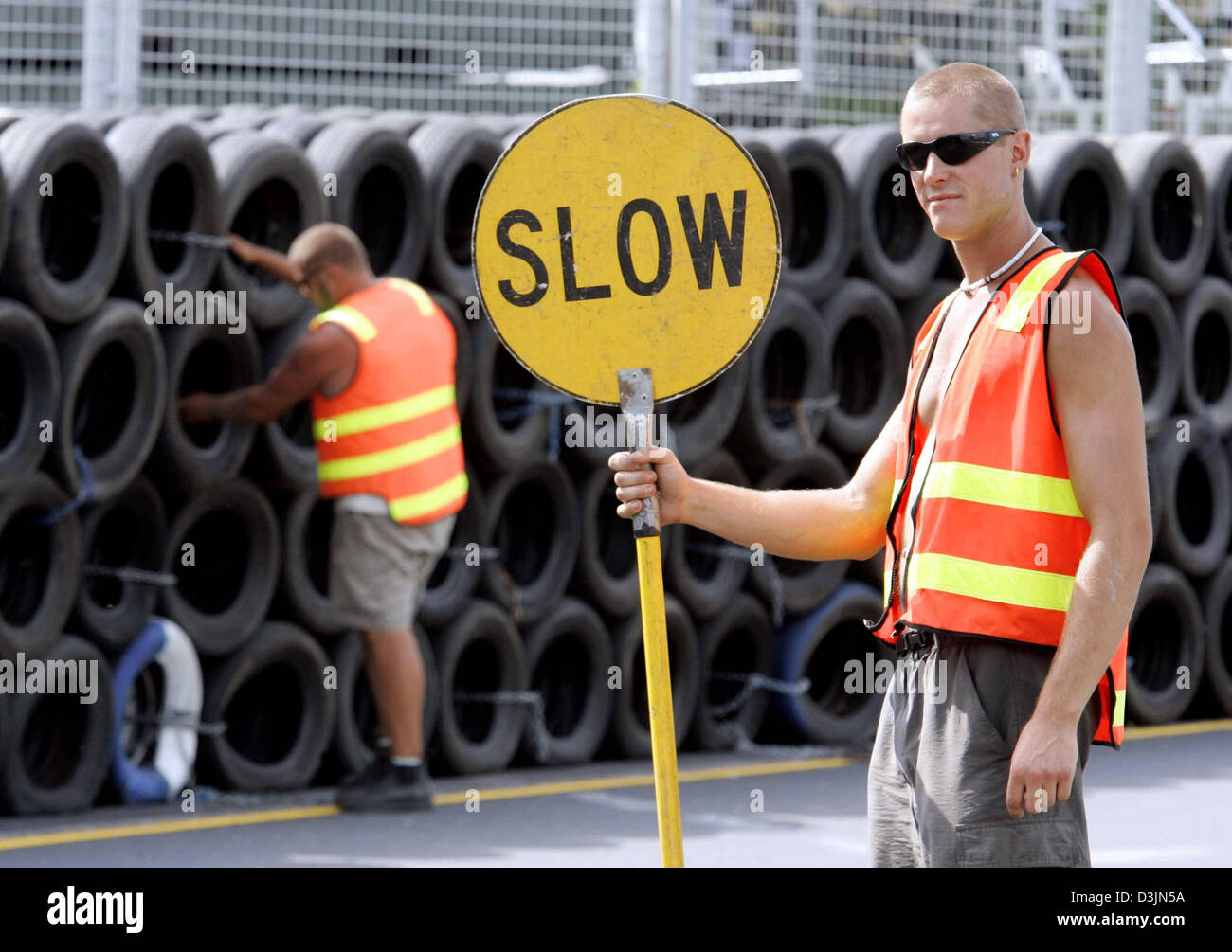 (Dpa) - roadman (R) contiene un segno nella sua mano che recita "bassa", mentre il suo collega sulla pista barriera in pile di pneumatici al 'Albert Park' circuito di Formula Uno a Melbourne, Australia, Martedì, 01 marzo 2005. La prima gara del 2005 Formula Uno Stagione, l'Australian Grand Prix, inaugura la domenica. Foto Stock