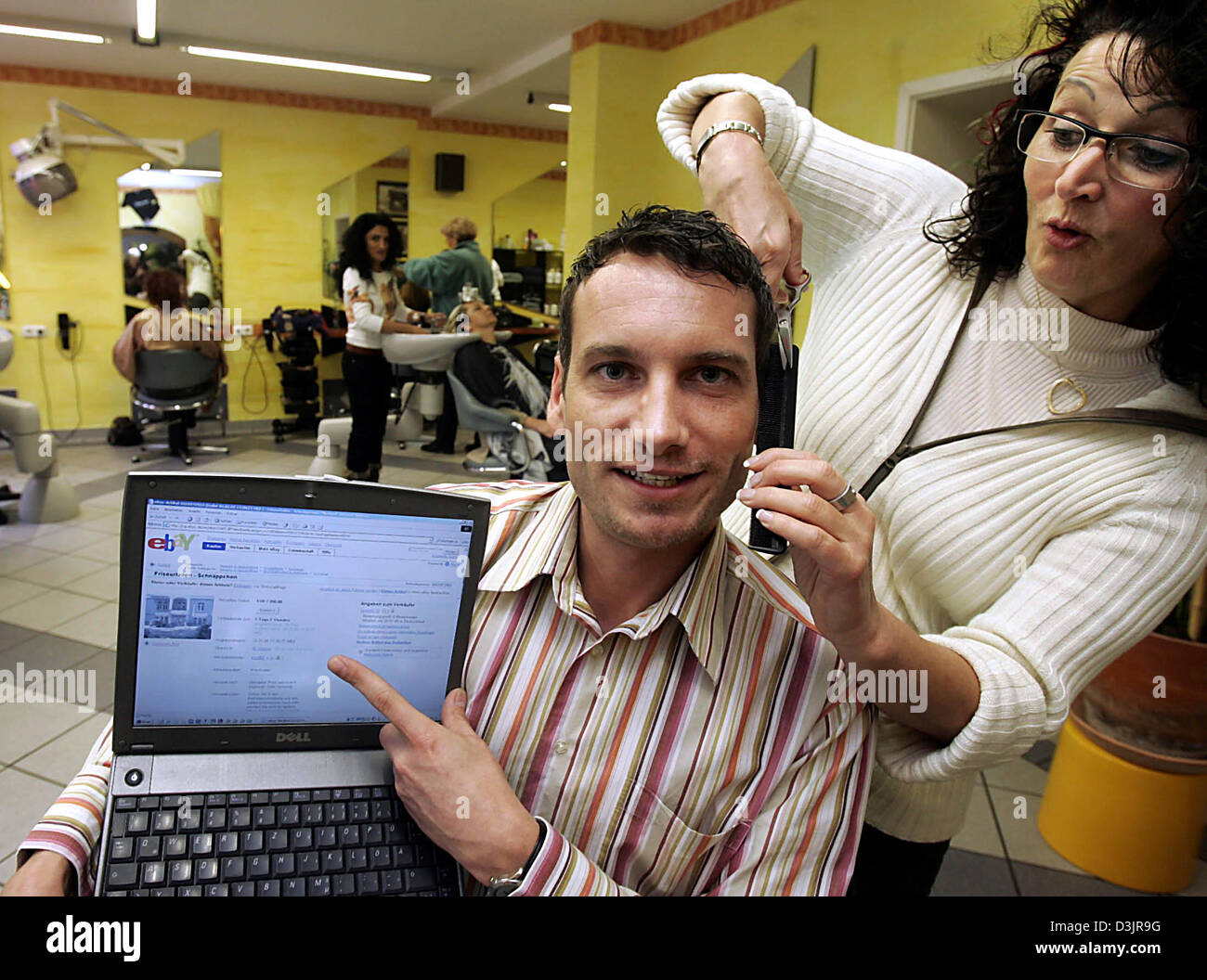 (Dpa) - Dagmar Groh (R) di tagliare i capelli del suo capo Pietro Cristo (C) che punti alla sua offerta su Ebay dal parrucchiere negozio 'Haarschneiderei' (taglio di capelli) di Wiesbaden, Germania, 28 gennaio 2005. Proprietario Cristo vuole asta le salon insieme con i suoi dipendenti presso le aste internet sito web ebay. Dal martedì (25 gennaio 2005) circa 7 mila euro sono stati offerti per la sho Foto Stock