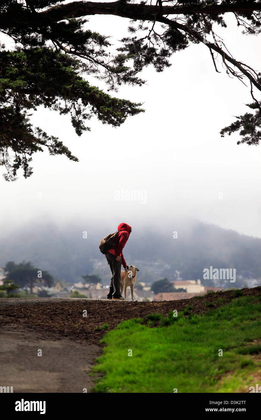 Ragazza con un cane su di una collina su uno sfondo di una nebbia. San Francisco, Alamo Square Foto Stock