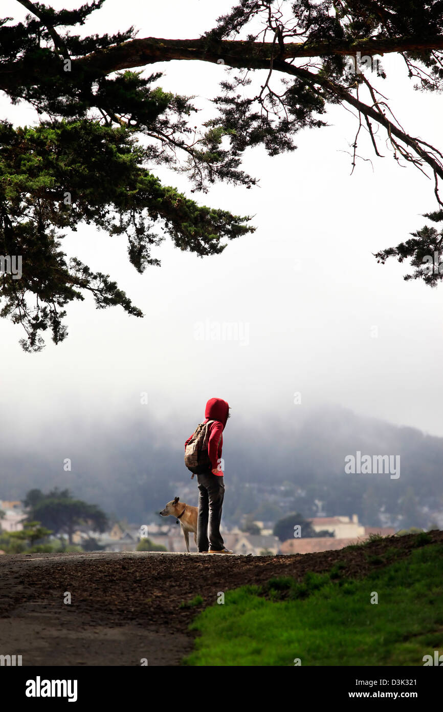 Ragazza con un cane su di una collina su uno sfondo di una nebbia. San Francisco, Alamo Square Foto Stock