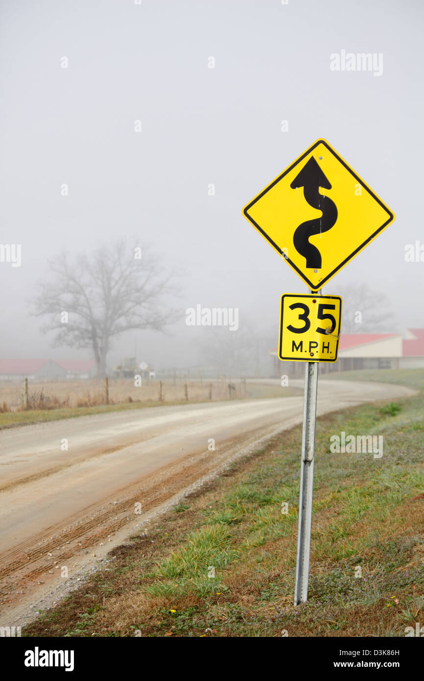 Strada tortuosa segno su una mattinata nebbiosa, North Carolina, STATI UNITI D'AMERICA Foto Stock