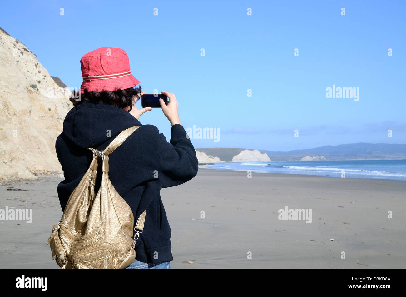 Donna presso la spiaggia di scattare le foto con il suo cell Foto Stock