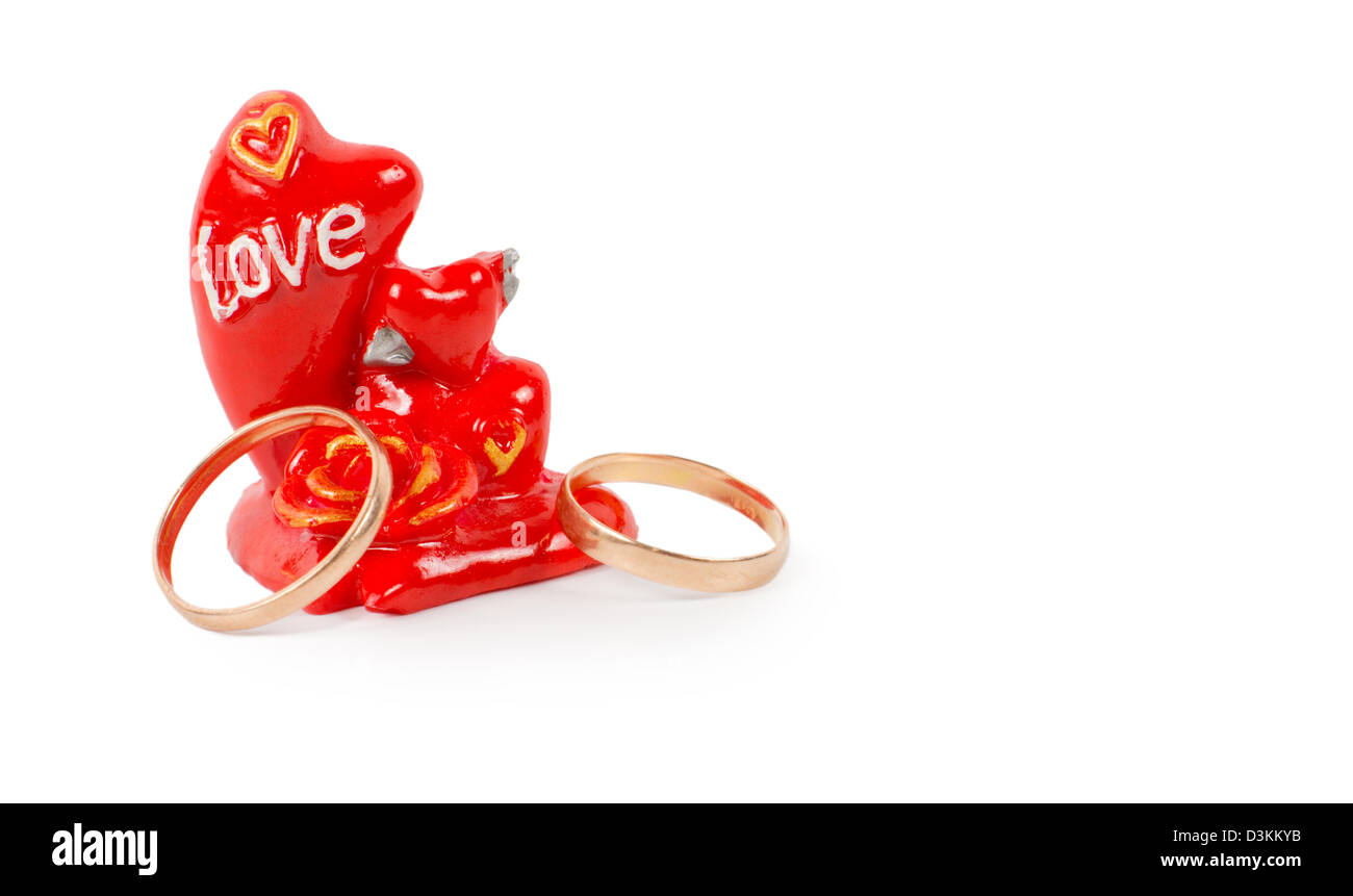 Due anelli in oro con un token di amore in forma o un ornamento di rosso con la scritta la parola amore Foto Stock