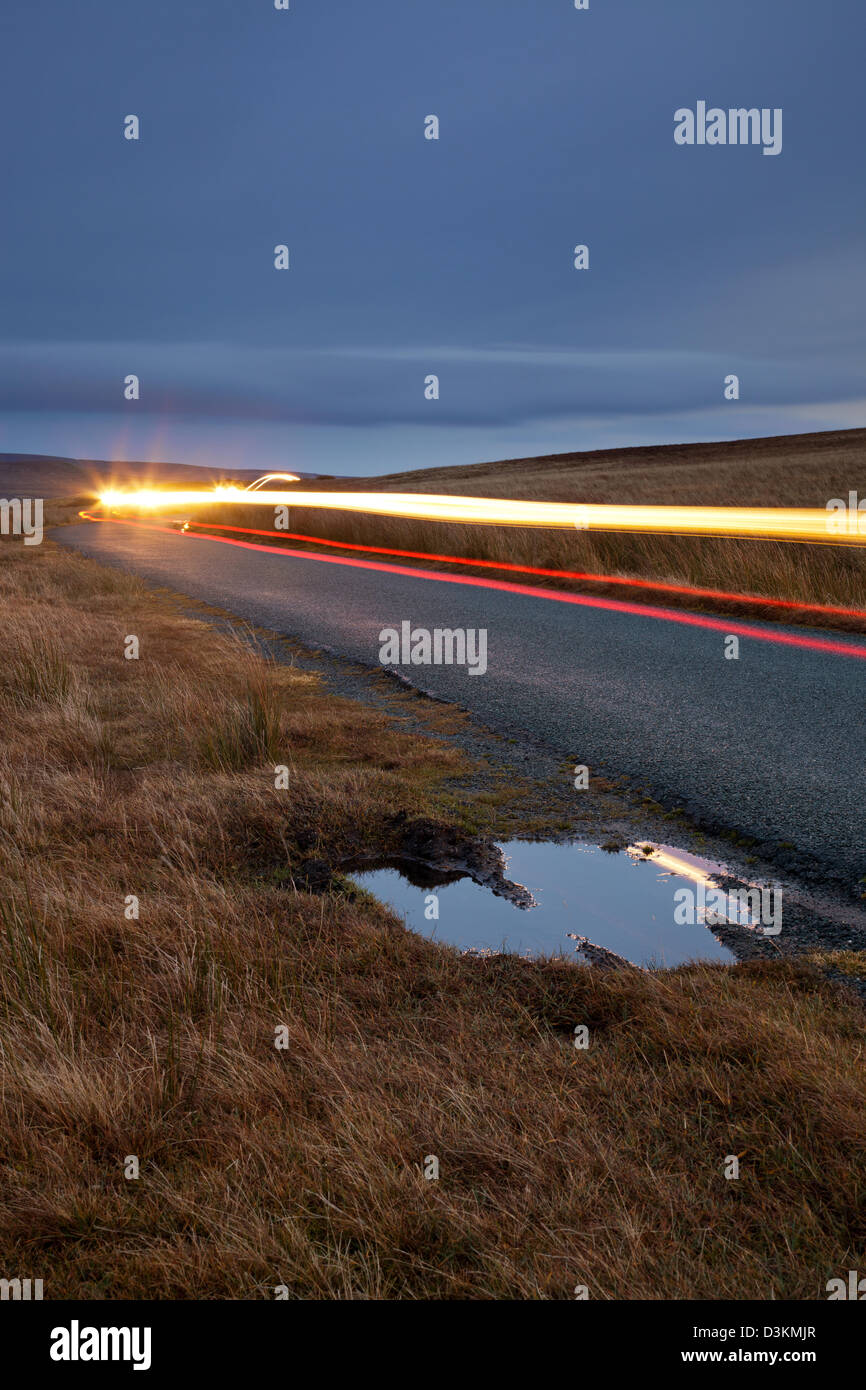 Sentieri di luce dal passaggio di vetture che viaggiano lungo una strada nella parte Swaledale dello Yorkshire Dales. Foto Stock