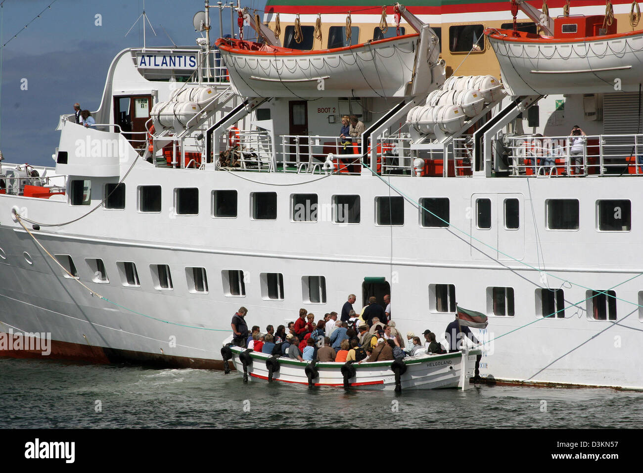 (Dpa file) - l'immagine mostra i turisti in una piccola barca di fronte alla grande stazione balneare cruiser 'Atlantis a Helgoland, Germania, 26 giugno 2005. Poiché le grandi navi hanno per ancorare davanti alla costa, i turisti sono trasportati in piccole barche per l'isola. Foto Stock