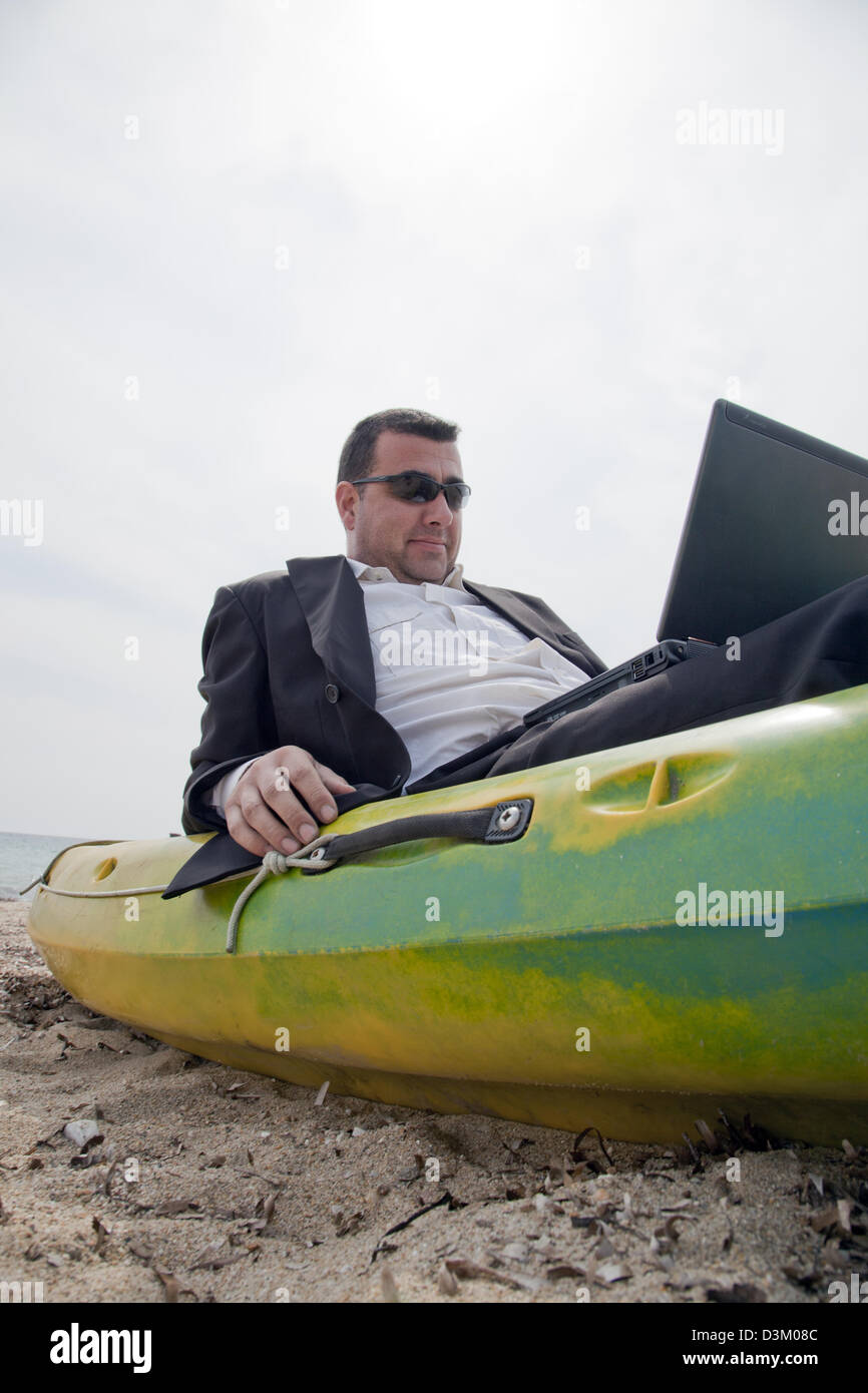 Imprenditore lavorando a sedersi sulla sommità kayak Foto Stock