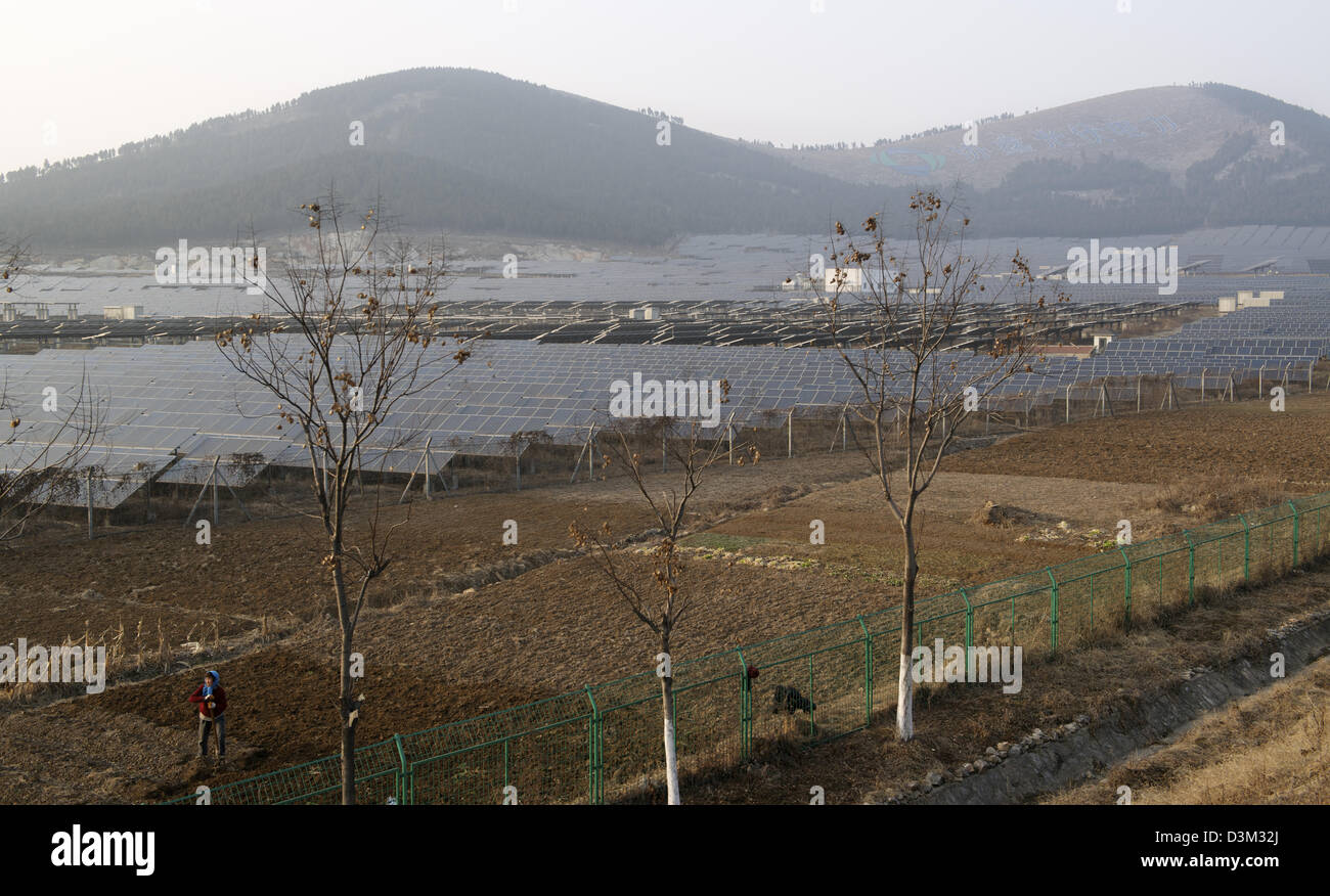 Una donna cinese agricoltore lavora nel campo vicino a una potenza fotovoltaica solare Impianto a Xuzhou, provincia dello Jiangsu, Cina. 16-Feb-2013 Foto Stock