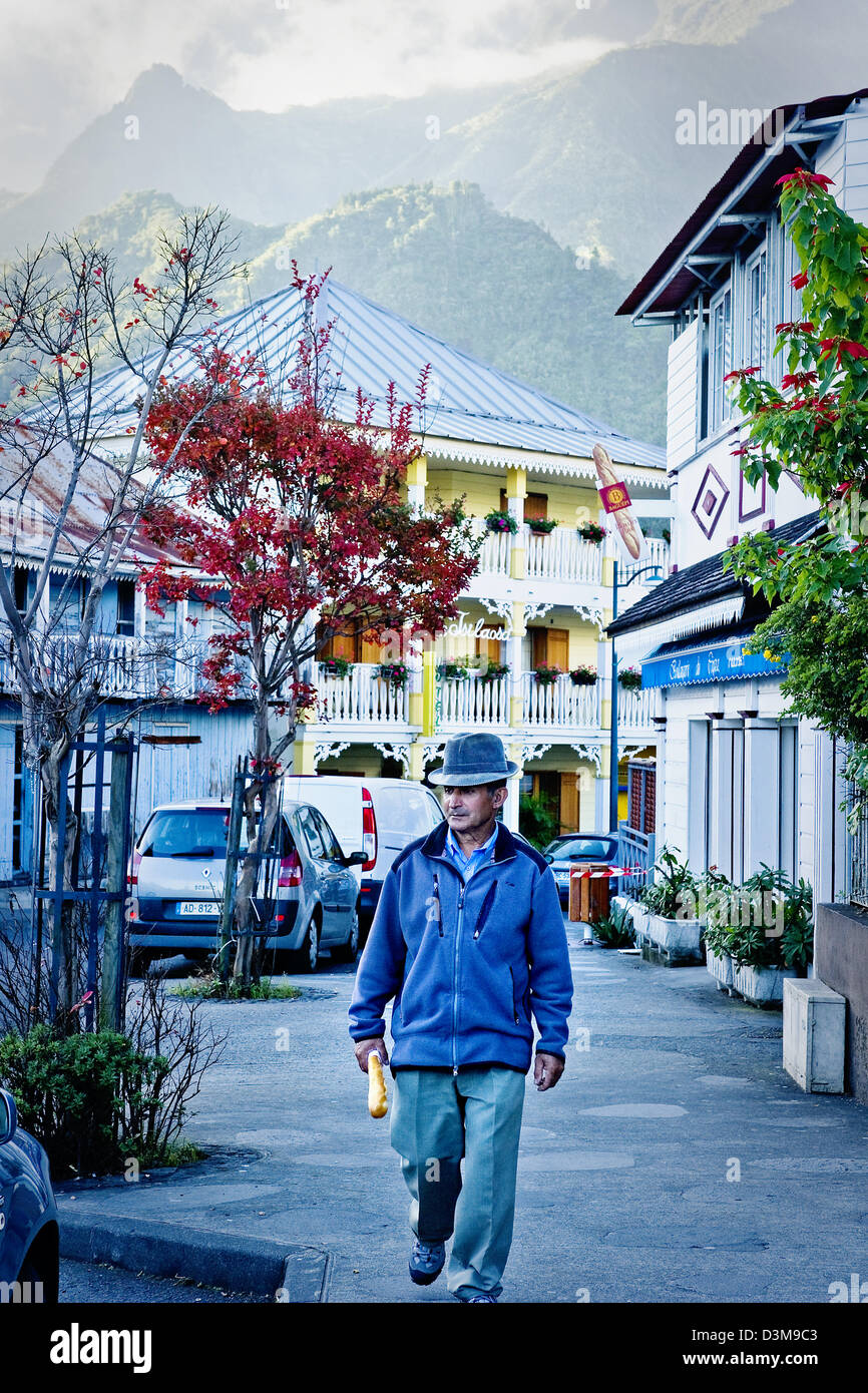 Un uomo locale con la possibilità di passeggiare per la strada tenendo baguette fresche, main high street, Cilaos, Isola di Reunion (Francese), l'Oceano Indiano Foto Stock