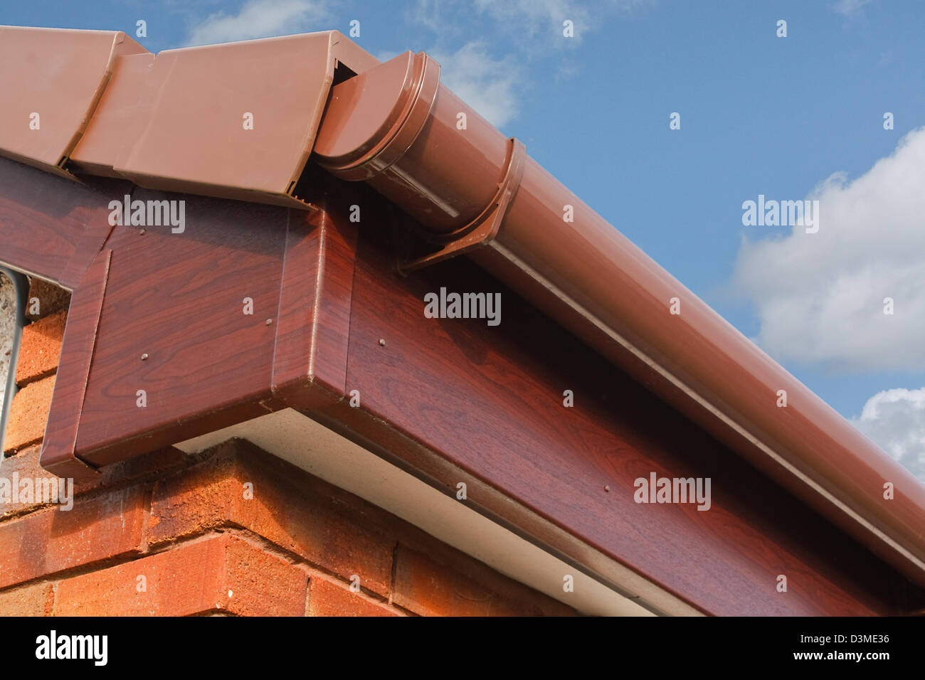 Close up marrone effetto legno PVCu o plastica intradosso, lo scudo e la grondaia sulla nuova e moderna costruzione di immobili residenziali Foto Stock