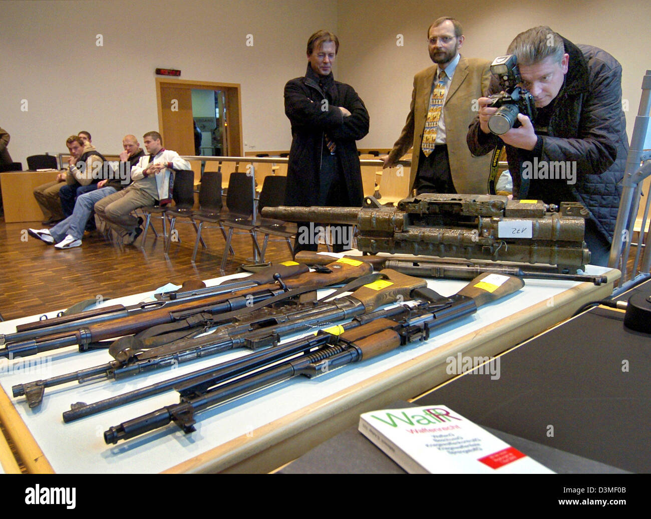 Fotografi di scattare foto illegale di pistole e fucili che sono sul display come prova su un tavolo presso il tribunale regionale di Augsburg, Germania, Mercoledì, 22 febbraio 2006. Due uomini hanno per rispondere in tribunale per violazione della legge tedesca sul controllo dell'arma. Essi sono accusati di possesso illegale di pistole di macchina automatica fucili di assalto, esplosivi, bombe a mano e più di 1.000 cicli Foto Stock