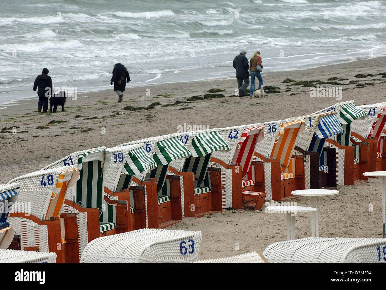 Passeggiata turistica lungo il litorale non impressionati dal focolaio di influenza aviaria in Timmendorfer Strand, Germania, 25 febbraio 2006. In primo piano beachchairs sono stati condizionati per i visitatori di un festival invernale. Foto: Wulf Pfeiffer Foto Stock