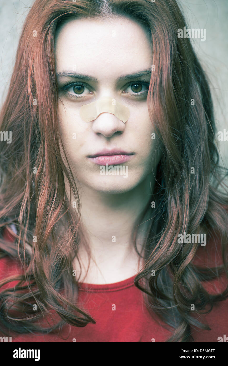 Ritratto di una giovane donna con una band-aiuto sul naso Foto Stock