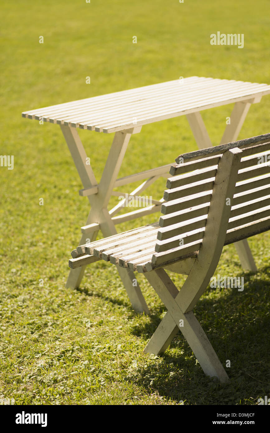 Estate in scena con erba verde, bianco tavolo in legno e banco nel giardino soleggiato Foto Stock