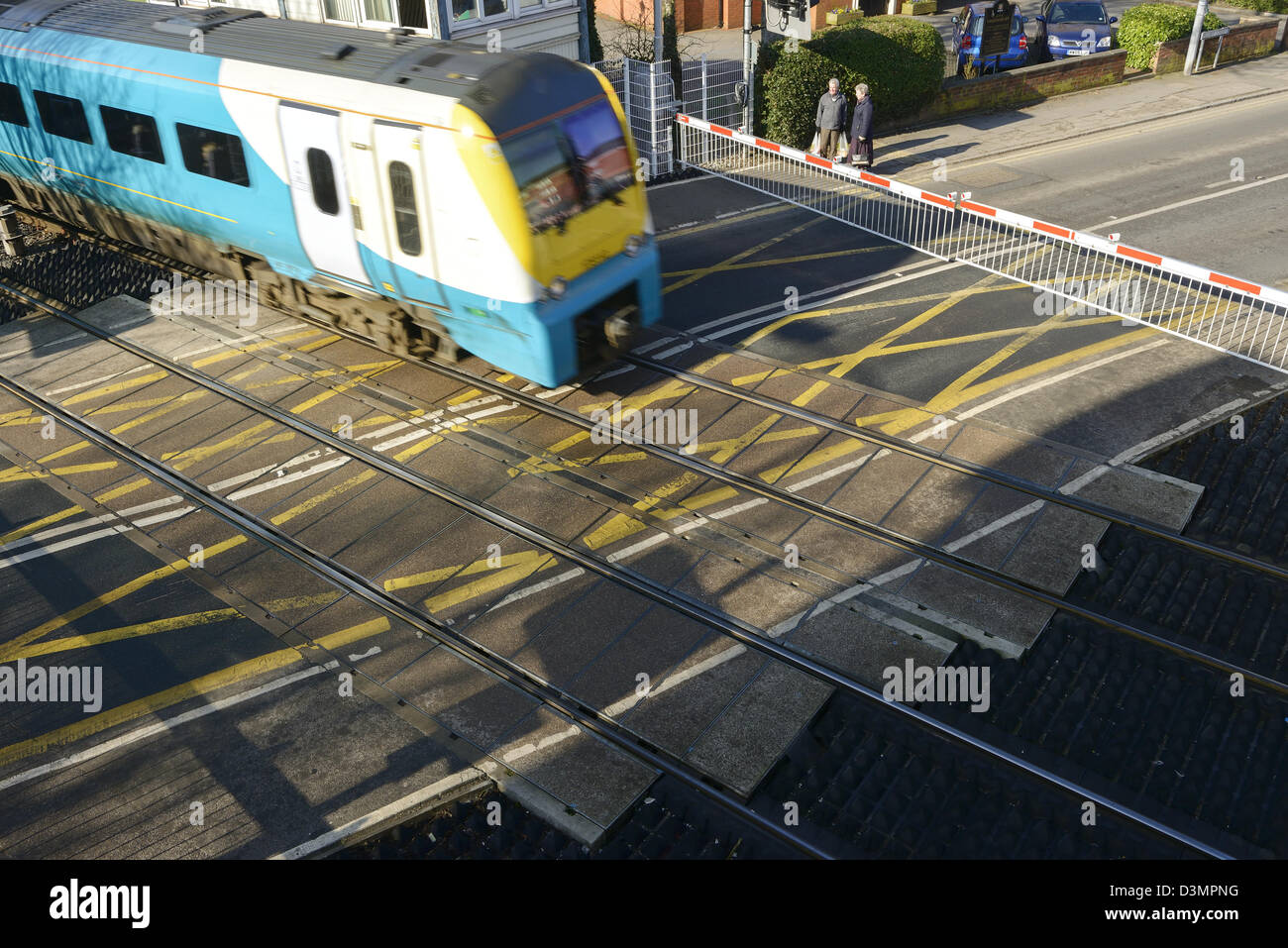 Un treno attraversare una strada in corrispondenza di un passaggio a livello Foto Stock