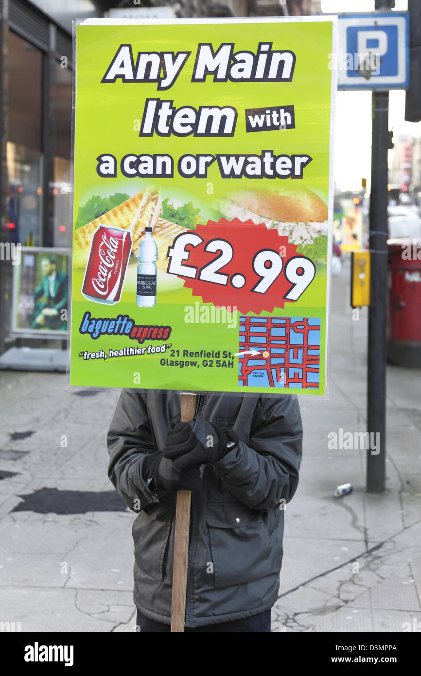 Una persona che ha un cartello che fa pubblicità a cibo e bevande per la vendita da Baguette Express nel centro di Glasgow, Scozia, Regno Unito Foto Stock