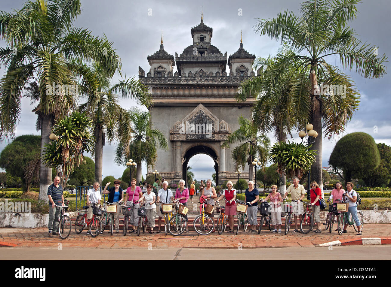 I turisti sulle biciclette in posa davanti Patuxai / Vittoria Gate / Gate del trionfo a Vientiane, Laos, sud-est asiatico Foto Stock