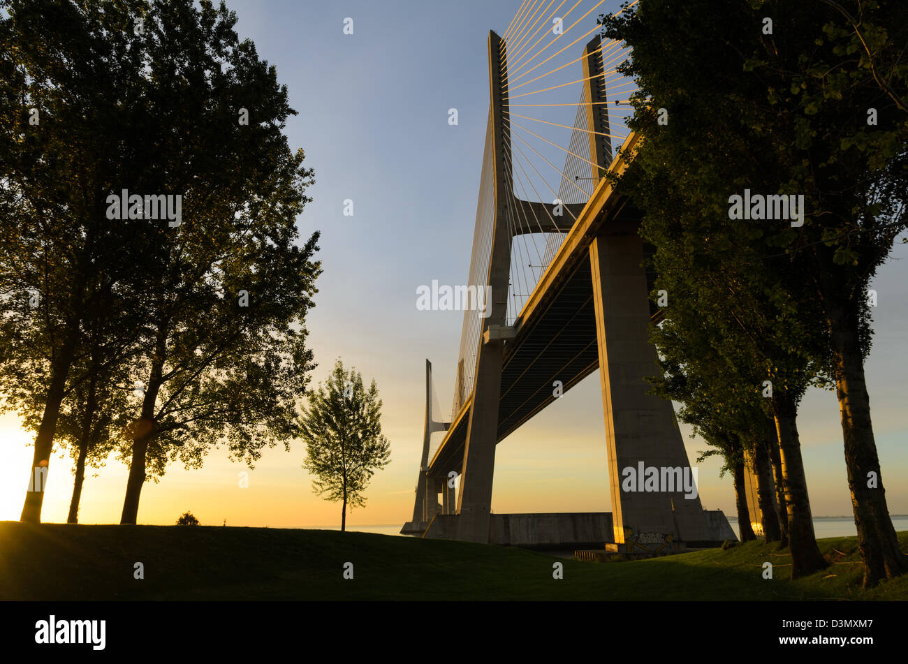 Dal ponte Vasco da Gama a Lisbona, Portogallo durante il tramonto con alberi in primo piano Foto Stock