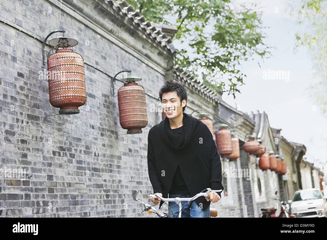Sorridente giovani asiatici uomo cinese in bicicletta, Pechino, Cina Foto Stock