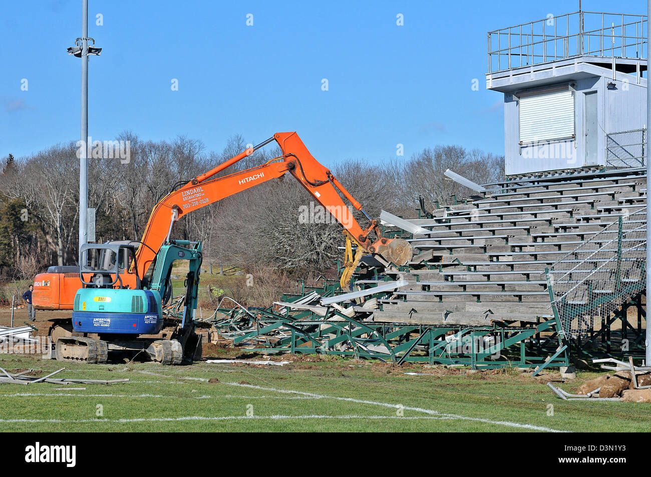 Un wrecker abbatte le gradinate in uno stadio di calcio in Madison CT USA come la città si prepara a costruire una nuova. Foto Stock